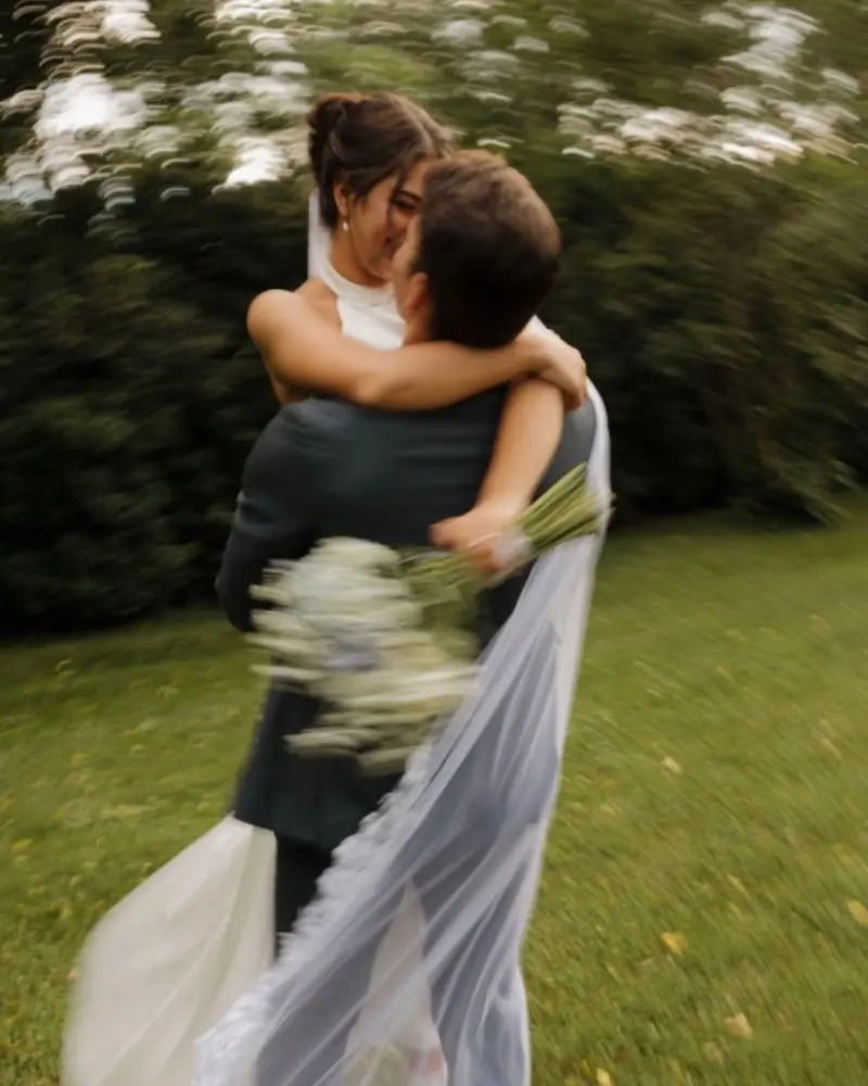 A bride and groom holding each other, her veil streaming out behind them