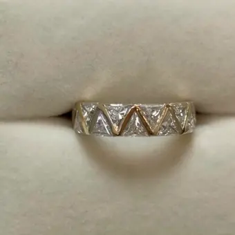 A gold band with a row of square stones set between polished zigzag lines