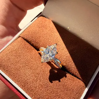A marquise diamond ring in yellow gold resting in a red ring box
