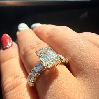 An emerald cut diamond with an emerald cut band, worn on a hand in the car